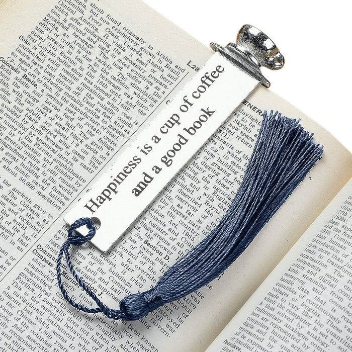 bookmark with quotes by Judi Glover Art. The metal bookmark has the quote happiness is a cup of coffee and a good book. The metal bookmark is shown laying on a book. 