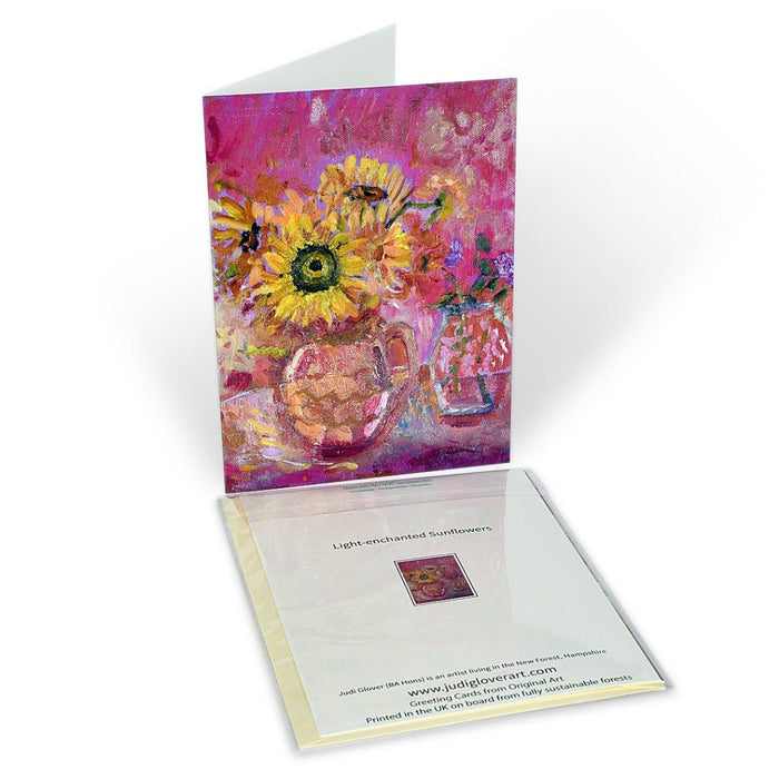 Art Greeting Card. A fine art greeting card made from original art. The original art is of sunflowers on a table in a vase. Strong yellow and pink colours. The original painting art card was painted by Judi Glover. It is available as a fine art greeting card at Judi Glover Art.