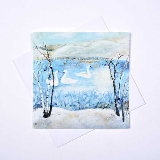 Three white swans swimming on a tranquil blue lake surrounded by snow-covered trees in Judi Glover's A Winter Wonderland set of 6 Christmas cards
