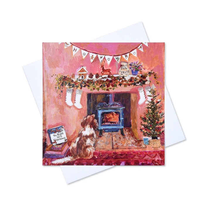 Christmas-themed greeting card with a dog by a fireplace and festive decorations.