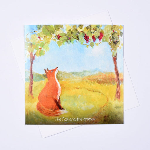 The Fox and the Grapes greeting card — original art by Judi Glover showing a fox gazing up at red grapes hanging from a vine against a golden countryside landscape