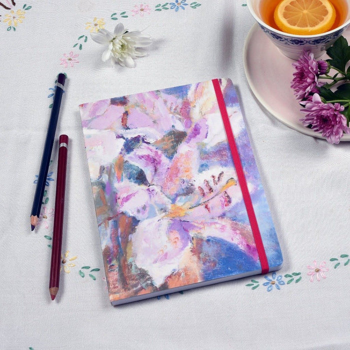 Picture showing the lilies notebook on a table. You can see the pink elastic enclosure which matches the floral notebook